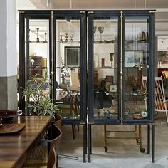 a room filled with lots of furniture next to a wooden table and chair in front of glass doors