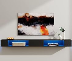 an abstract painting hangs on the wall above a shelf