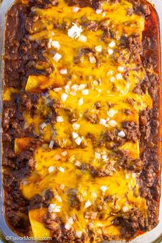 an enchilada casserole in a glass dish with cheese on top