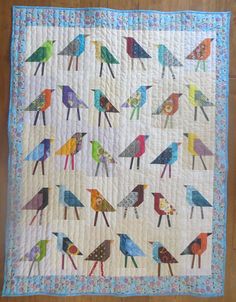 a quilted wall hanging with colorful birds on it