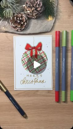 a christmas card with a bow on it next to crayons and pencils