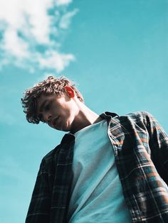 a young man standing in front of a blue sky