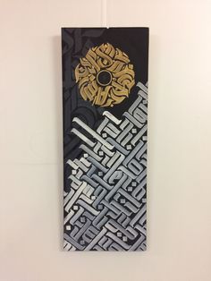 a black and white painting hanging on a wall with gold accents in the center is an abstract design