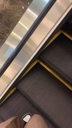 an escalator with someone's feet on the ground next to it,