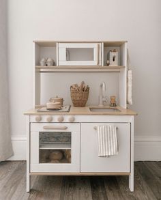 a white play kitchen with an oven, sink and microwave