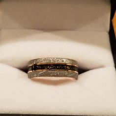 two gold wedding bands in a box with white furnishing and black diamond accents