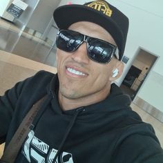 a man wearing sunglasses and a hat sitting in an airport