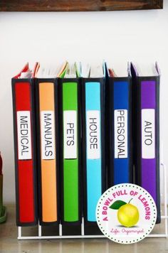 several books are lined up on a shelf next to a wine bottle and an apple