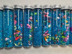 a row of blue jars filled with lots of different types of beads and toys next to each other