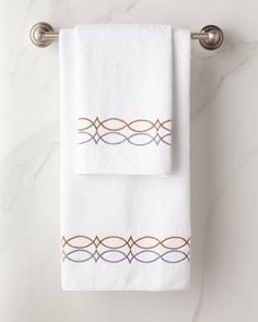 two white towels hanging on a towel rack next to a marble counter top with an orange and gray border