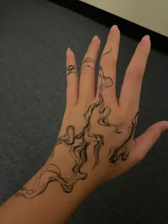 a woman's hand with black ink on it and wavy lines drawn across the palm