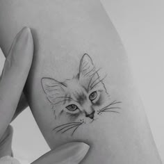 a black and white photo of a cat's face on the side of a woman's thigh