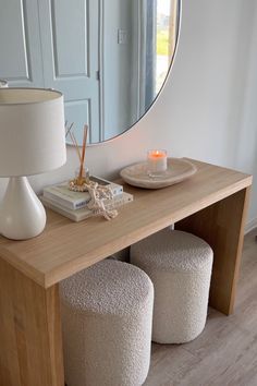 a mirror sitting on top of a wooden table next to two stools and a lamp