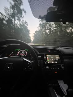 the dashboard of a car on a road with trees in the background