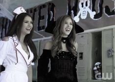 two women dressed in costumes standing next to each other and smiling at the same time