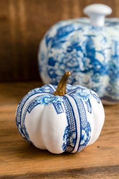 two blue and white pumpkins sitting on top of a wooden table next to each other