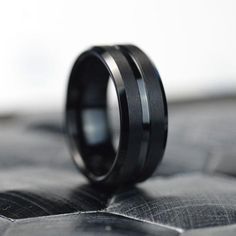 a black wedding band is sitting on top of a piece of cloth with the ring in it's center