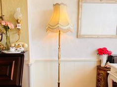 a lamp that is on top of a wooden table next to a dresser and mirror