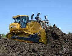 a bulldozer digging through the dirt on a sunny day