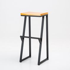 a wooden stool sitting on top of a white floor next to a black metal frame