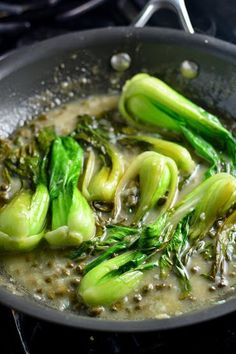 broccoli being cooked in a wok on the stove top with some oil