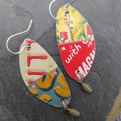 two pairs of colorful earrings sitting on top of a stone floor next to each other