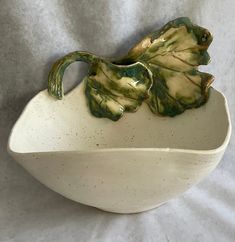 a white bowl with green leaves on it