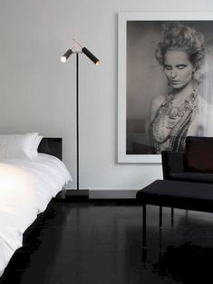 a white bed sitting next to a black and white chair in a room with a painting on the wall