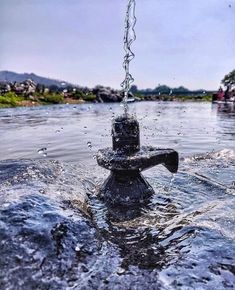 a black fire hydrant is in the middle of some water and it's spouting