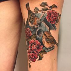 a woman's thigh with flowers and birds on it, next to a cross