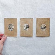 three small pictures are being held up by someone's hand