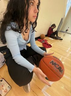 a woman is holding a basketball on the floor