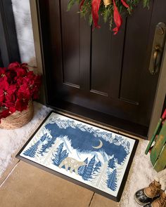 a door mat with a bear on it next to a christmas wreath and red poinsettis