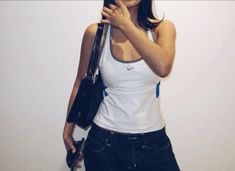 a woman holding an umbrella and posing for the camera in front of a white wall