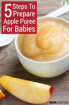 a bowl filled with apple puree next to an apple slice and spoon on a wooden table