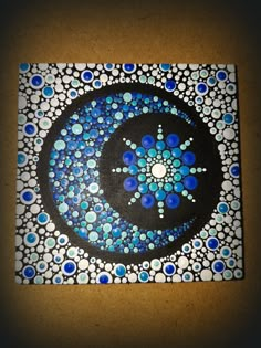 a blue and white painting on a wall with circles in the center, surrounded by dots