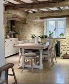 a dining room table and chairs in front of a window with an open brick wall