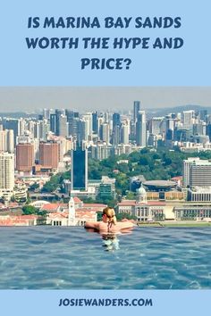 a man swimming in the middle of a body of water with buildings in the background