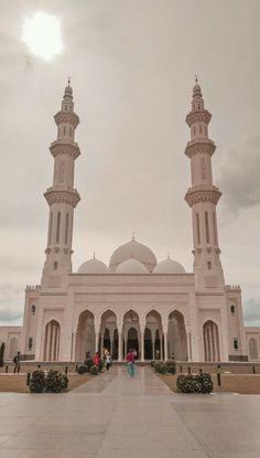 two tall white buildings sitting next to each other on top of a cement floored area