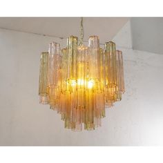 a yellow chandelier hanging from the ceiling in a white walled room with exposed lighting