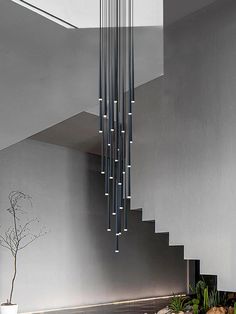 a modern chandelier hanging from the ceiling in a room with stairs leading up to it