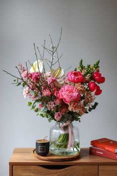 a vase filled with flowers sitting on top of a wooden table next to a book