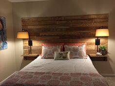 a bed with two lamps on either side and a wooden headboard above the bed