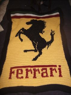 a crocheted afghan with the word ferrari written in red and black on it