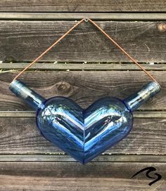 a blue heart shaped vase hanging on a wooden wall