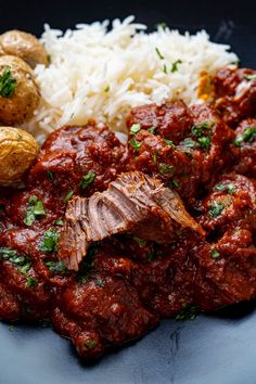 meat, rice and potatoes on a plate with parsley sprinkled on top