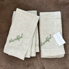 three linen napkins with embroidered words on them