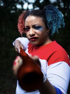 a woman with blue and red hair holding a bottle