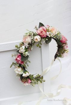 a wreath with pink flowers and greenery hanging from the side of a white door