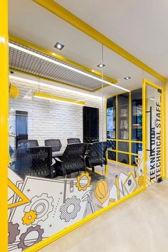 an office with yellow and white walls, black chairs and a large mural on the wall